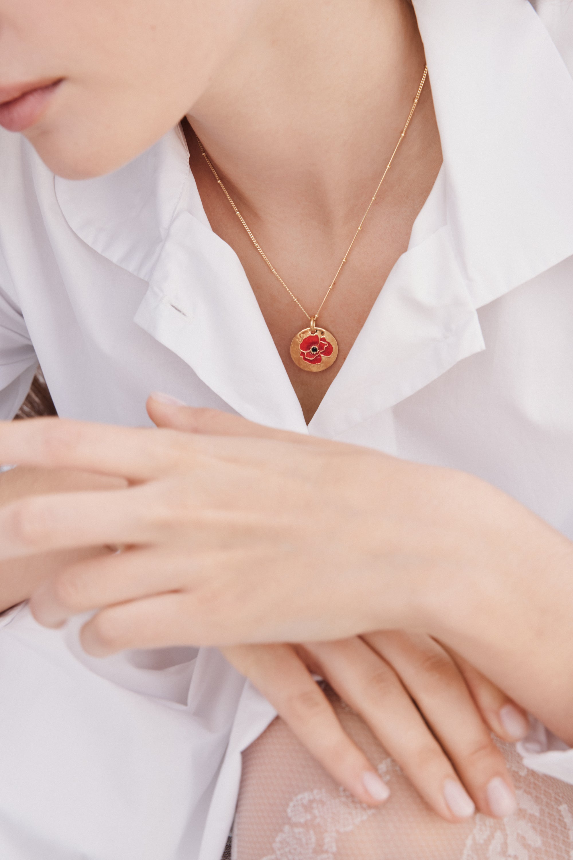 Pendant necklace with poppy on gold medallion